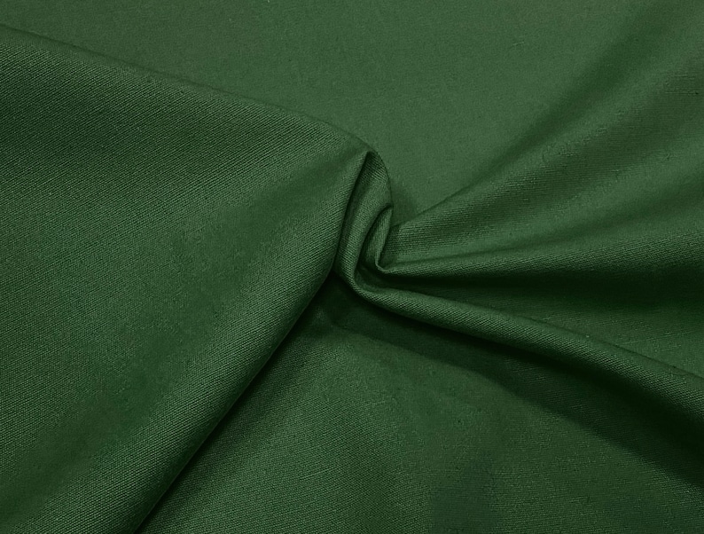 May include: A close-up of a dark green fabric with a smooth, even texture. The fabric is folded in a way that shows its drape and softness.