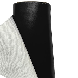 May include: A roll of black fabric with a white backing. The fabric is rolled up and the white backing is visible on the side.