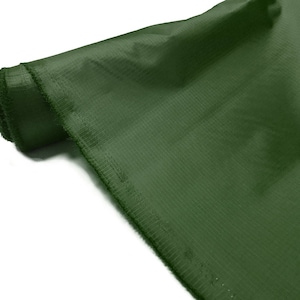 May include: A roll of dark green fabric with a textured surface. The fabric is folded and rolled up, with the edges visible.