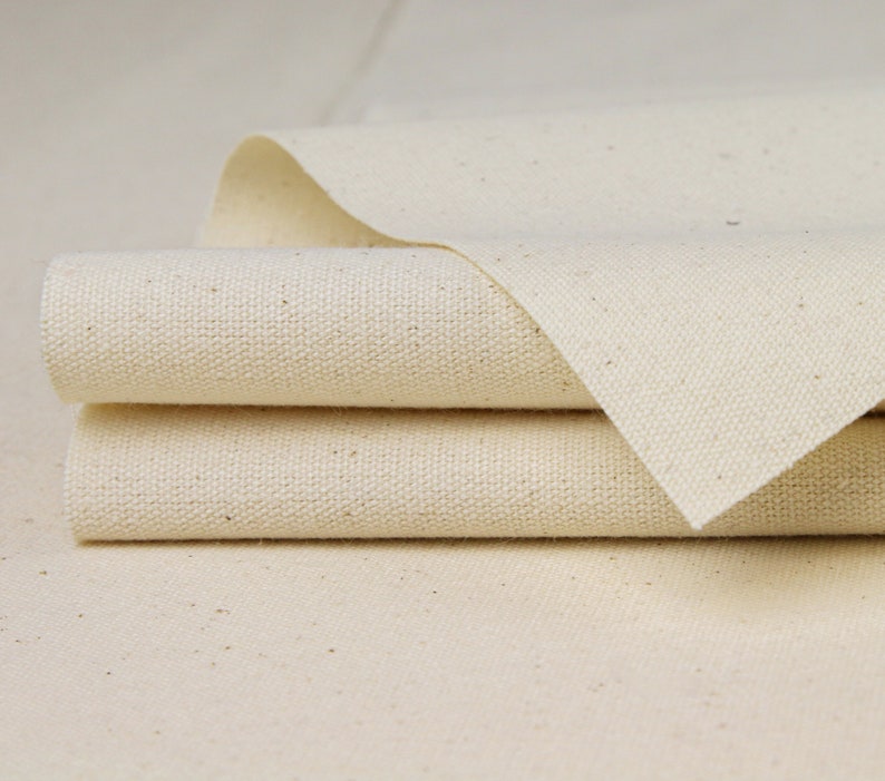May include: Close-up of three layers of natural white canvas fabric folded together. The fabric has a subtle texture and a slightly off-white color.