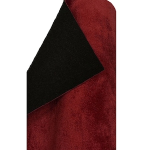 May include: A close-up of a burgundy velvet fabric with a black backing. The fabric is folded in half, showing both sides.