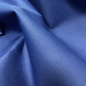 May include: Close-up of a blue fabric with a textured surface. The fabric has a subtle, woven pattern.