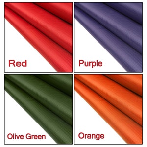 May include: Four fabric swatches in different colors: red, purple, olive green, and orange. The fabric has a woven texture.