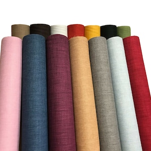 May include: A collection of 12 fabric rolls in various colours, including pink, blue, burgundy, beige, yellow, grey, light blue, and red. The fabric rolls are arranged in a semi-circle.