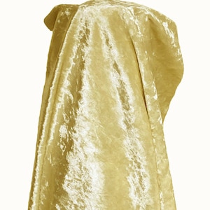 May include: A golden-yellow velvet fabric draped over an unseen form. The material has a soft, textured surface, with folds and shadows adding depth. The fabric's luxurious appearance is highlighted against a plain white background. The overall effect is elegant.