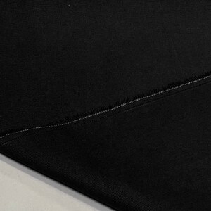 May include: Black fabric with a raw edge and a single stitch seam.