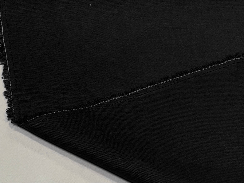May include: Black fabric with a raw edge and a single stitch seam.