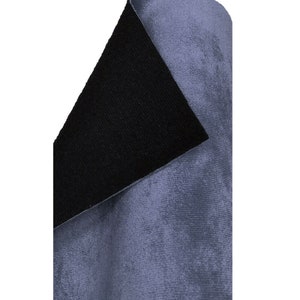 May include: A close-up of a rolled-up piece of fabric. The fabric has a soft, velvety texture and a muted blue-grey colour. The underside of the fabric is black, creating a contrast. The fabric is likely used for upholstery or clothing.