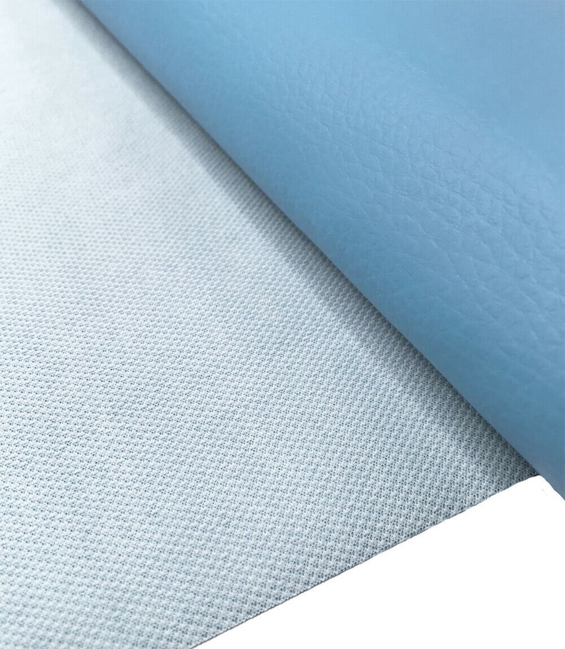 May include: A close-up of a light blue fabric with a textured surface. The fabric is folded over to reveal a white backing with a grid pattern.