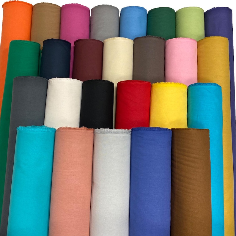 May include: A collection of rolled fabric in various colors, including orange, green, navy, pink, and yellow. The rolls are arranged vertically, showcasing the diverse color palette of the textile materials. The image highlights the texture and variety of the fabric.