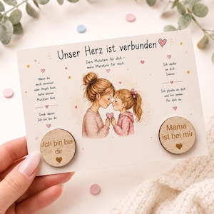 Könnte beinhalten: Eine Grußkarte mit dem Text "Unser Herz ist verbunden" und einer Illustration einer Mutter und eines Kindes, die ein Herz halten. Enthält zwei herzförmige Holz-Tokens mit Text. Rosa, blaue und weiße Akzente.