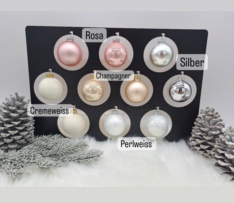 Pode incluir: Conjunto de 10 enfeites de Natal em v&aacute;rias cores, incluindo prata, champanhe, creme, branco p&eacute;rola e rosa. Os enfeites s&atilde;o exibidos em um fundo preto com os nomes das cores escritos abaixo de cada enfeite.