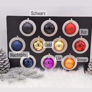 Pode incluir: Conjunto de 10 enfeites de Natal em v&aacute;rias cores, incluindo preto, dourado, vermelho, laranja, roxo, azul e prata. Os enfeites s&atilde;o exibidos em um fundo preto com os nomes das cores escritos abaixo de cada enfeite.