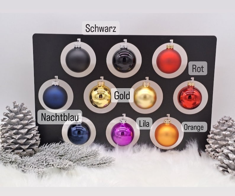 Pode incluir: Conjunto de 10 enfeites de Natal em v&aacute;rias cores, incluindo preto, dourado, vermelho, laranja, roxo, azul e prata. Os enfeites s&atilde;o exibidos em um fundo preto com os nomes das cores escritos abaixo de cada enfeite.