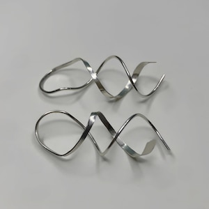 May include: A pair of silver spiral earrings. The earrings are made of a single piece of metal that is twisted into a spiral shape.