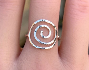 May include: A silver ring with a hammered finish featuring a double spiral design.