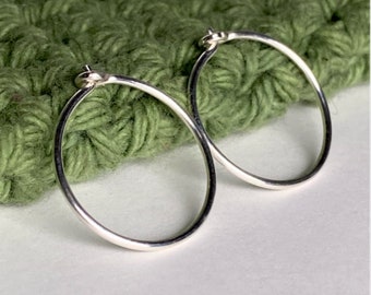 May include: A pair of silver hoop earrings. The earrings are simple and elegant, and they would be a great addition to any jewelry collection.