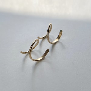 May include: A pair of gold-colored spiral ear cuffs. The cuffs are made of a thin, flexible metal and are designed to wrap around the ear.