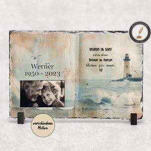 Könnte beinhalten: Eine Schiefertafel mit einem Foto eines älteren Mannes und eines jungen Mädchens, einem Leuchtturm und dem Text "Werner 1950-2023" und "Spuren im Sand vergehen Spuren im Herzen bleiben für immer."