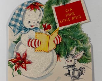 Puede incluir: Tarjeta de Navidad vintage con un muñeco de nieve con una bufanda a cuadros azul y blanco y mitones a rayas rojas y blancas. La tarjeta incluye un letrero rojo que dice "TO A DEAR LITTLE NIECE". También se presenta un conejito gris y un árbol de Navidad.