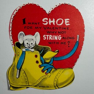 May include: Vintage Valentine's Day card in a heart shape. The card features a yellow shoe with blue laces and a small mouse peeking out. Text on the card reads "I want shoe for my Valentine. Why not string along with me?"