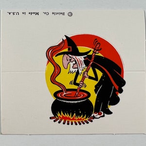 May include: A black and white illustration of a witch stirring a cauldron with a red liquid. The witch is wearing a black hat and robe. The cauldron is sitting on a bed of red flames. The text "Belistle Co. Made in U.S.A." is printed on the image.