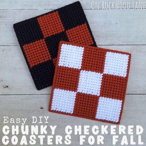 May include: Two handmade, square coasters with a checkerboard pattern. One coaster features black and orange squares, while the other has white and orange squares. The text "Easy DIY CHUNKY CHECKERED COASTERS FOR FALL" is at the bottom.