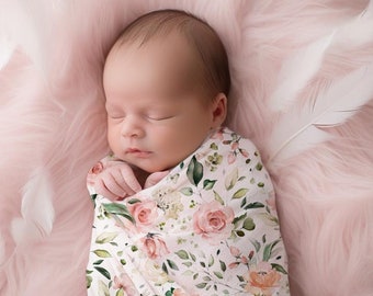 Könnte beinhalten: Ein neugeborenes Baby ist in ein weißes Swaddle mit einem rosa-grünen Blumenmuster gewickelt. Das Baby schläft friedlich auf einer rosa flauschigen Decke.
