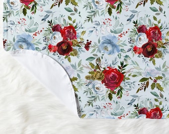 Könnte beinhalten: Eine weiche, blaue und weiße Babydecke mit einem Blumenmuster aus roten, weißen und blauen Blumen. Die Decke hat eine weiße Rückseite.