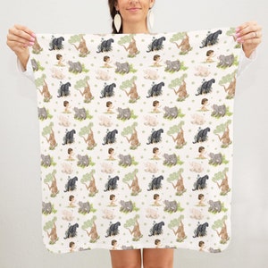 Op de afbeelding: Witte babydeken met een herhalend patroon van een jongen, een panter, een beer en een boom. Het patroon is in tinten bruin, groen en zwart.