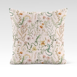 May include: A pink throw pillow with a floral pattern featuring green lizards, yellow, orange, and pink flowers, and green leaves.
