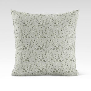 May include: A light green throw pillow with a white floral pattern. The pillow features a repeating pattern of small white flowers and green stems.