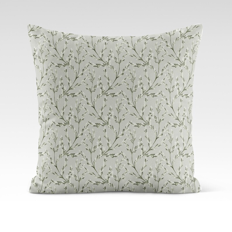 May include: A light green throw pillow with a white floral pattern. The pillow features a repeating pattern of small white flowers and green stems.