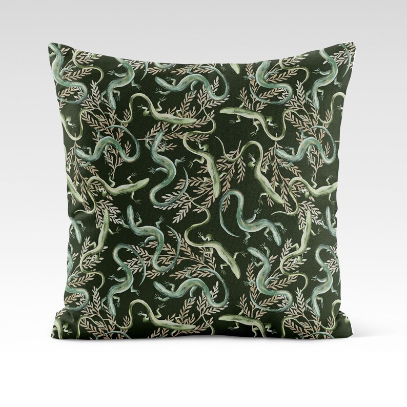 May include: A green throw pillow with a repeating pattern of stylized lizards and leafy branches.