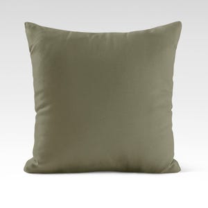 Op de afbeelding: Een vierkant, effen groen kussen met een zachte, pluche textuur.