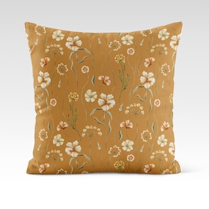 May include: A mustard yellow throw pillow with a white floral pattern. The pillow features a repeating pattern of small white flowers with green stems and leaves.