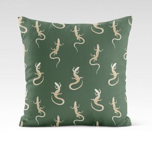 May include: A green throw pillow with a repeating pattern of beige lizards. The lizards are facing different directions and are in various poses.