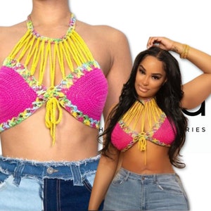 May include: A pink crochet halter top with yellow and green accents. The top has a tie closure in the front and a halter strap that ties at the back of the neck.