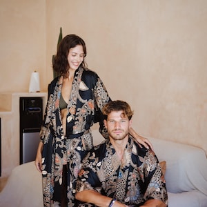 May include: A couple wearing matching black and gold patterned robes with intricate designs. The robes have a traditional Japanese style.