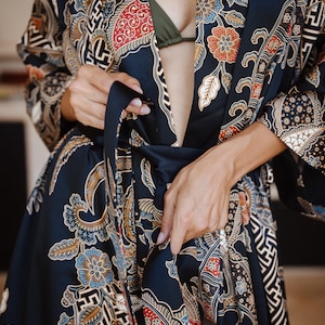 May include: A black silk robe with a colorful floral pattern. The robe is tied at the waist with a black sash.