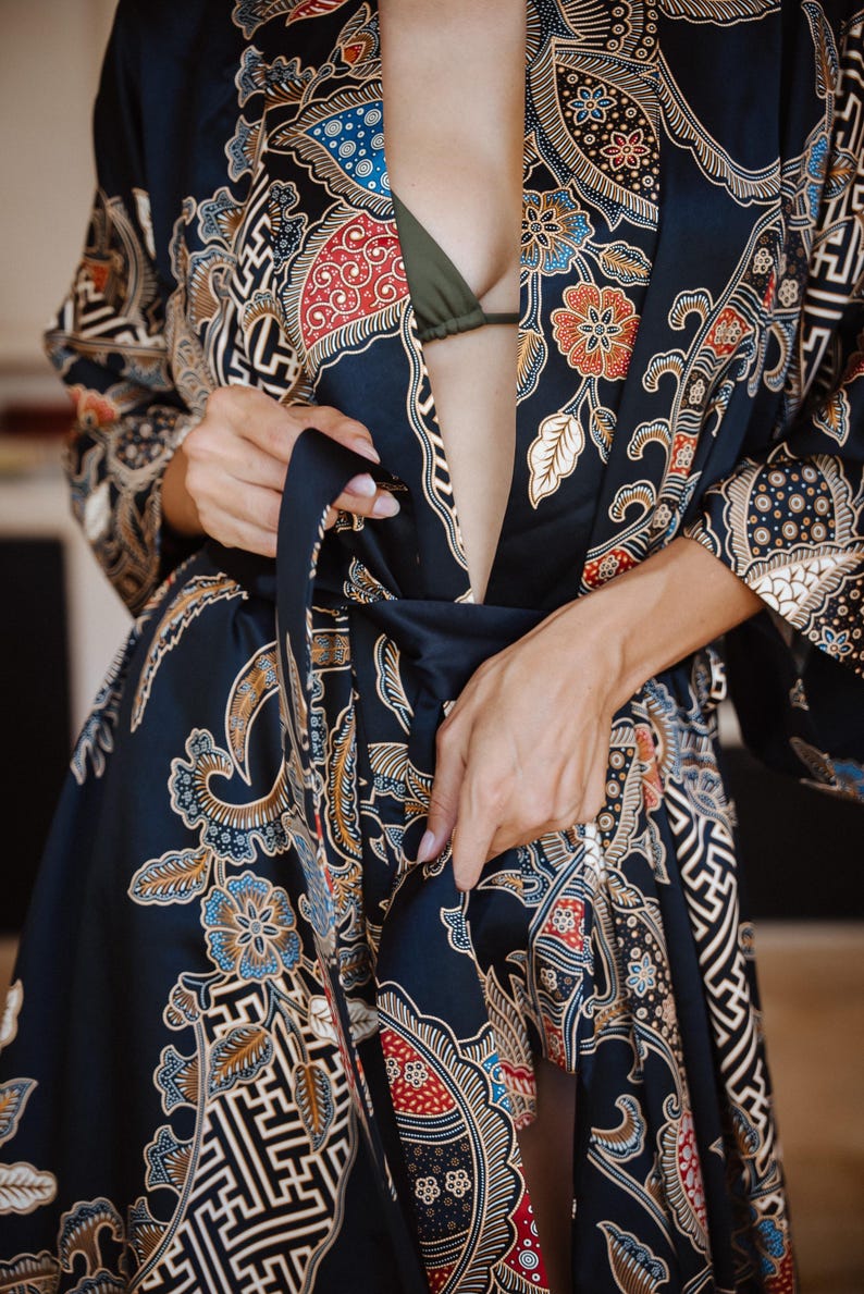 May include: A black silk robe with a colorful floral pattern. The robe is tied at the waist with a black sash.