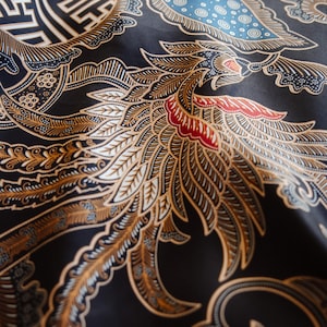 May include: Black fabric with a gold and white patterned design featuring a stylized bird with intricate details. The pattern also includes geometric shapes and leaves.