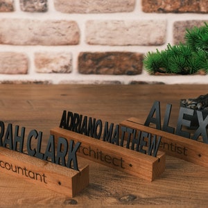 May include: Three wooden desk nameplates with black lettering. The nameplates read "Sarah Clark Accountant", "Adriano Matthew Architect", and "Alex Dentist".