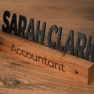 May include: A wooden desk nameplate with the name "SARAH CLARK" in black letters and the title "Accountant" engraved below.