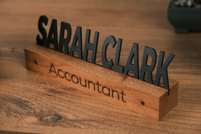 May include: A wooden desk nameplate with the name "SARAH CLARK" in black letters and the title "Accountant" engraved below.