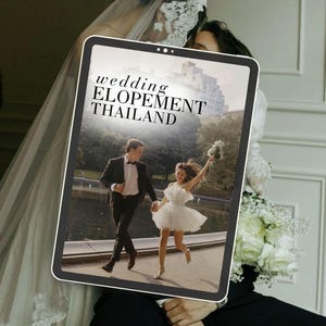 Könnte beinhalten: Ein Tablet zeigt ein Hochzeitsfoto mit dem Text "wedding ELOPEMENT THAILAND". Die Braut trägt ein kurzes weißes Kleid, der Bräutigam einen schwarzen Anzug. Eine Braut mit Schleier ist im Hintergrund.