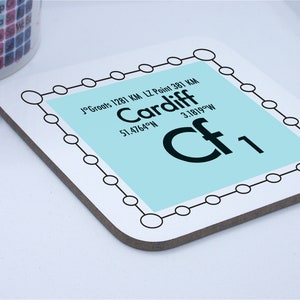 May include: A white coaster with a light blue square displaying the city name "Cardiff" and the element symbol "Cf". The coaster has a black border with connected circles. The text "J°Groats 1281 KM LZ Point 381 KM" is also visible.