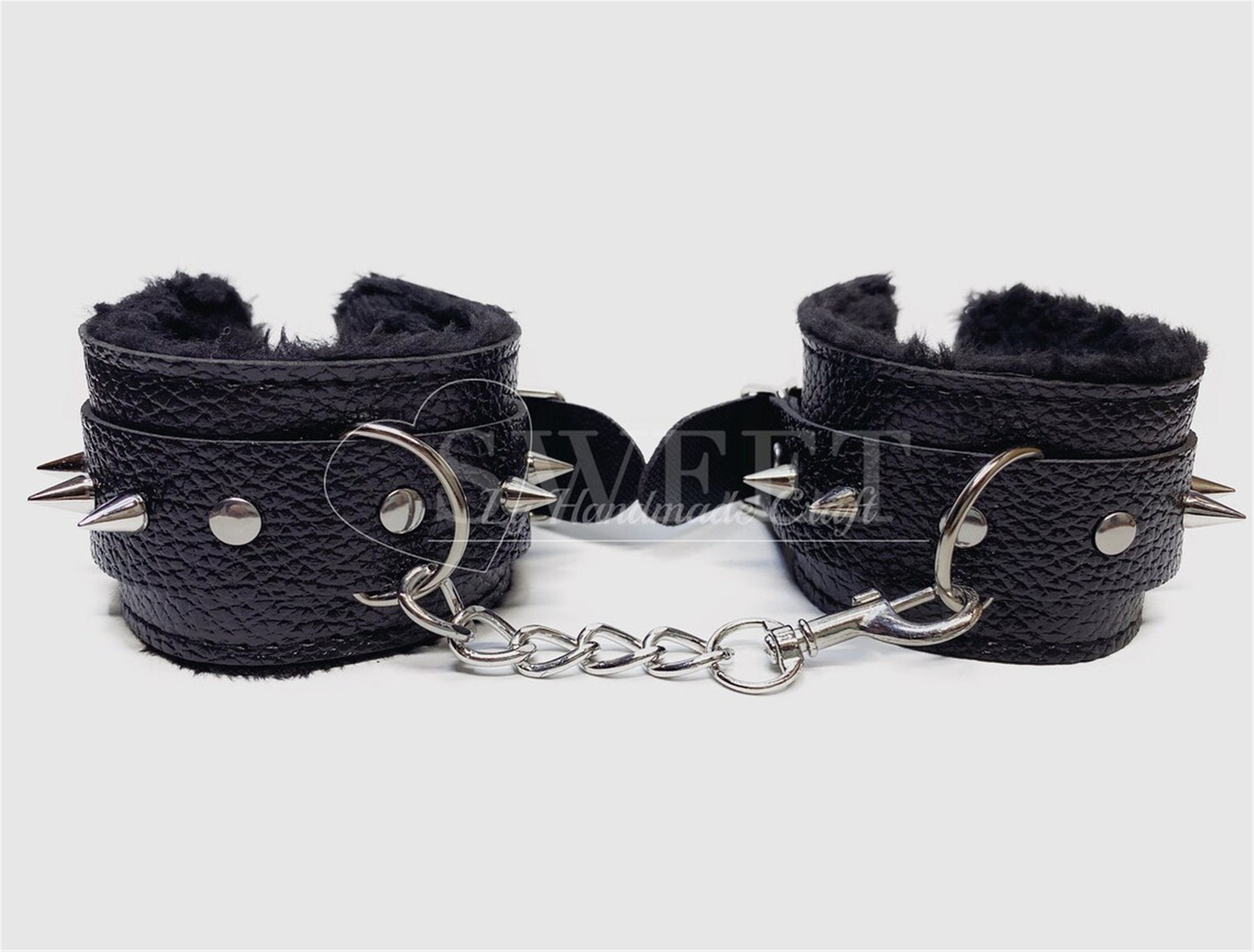 Black spiked faux leather BDSM cuffs with soft lining, punk bondage restraints for kinky handcuffs play.