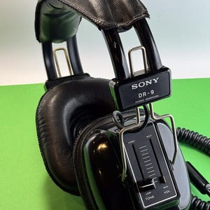 Pu&ograve; includere: Cuffie stereo Sony DR-9 nere con fascia in pelle nera e manopola di controllo del volume e del tono. Le cuffie hanno un cavo a spirale.