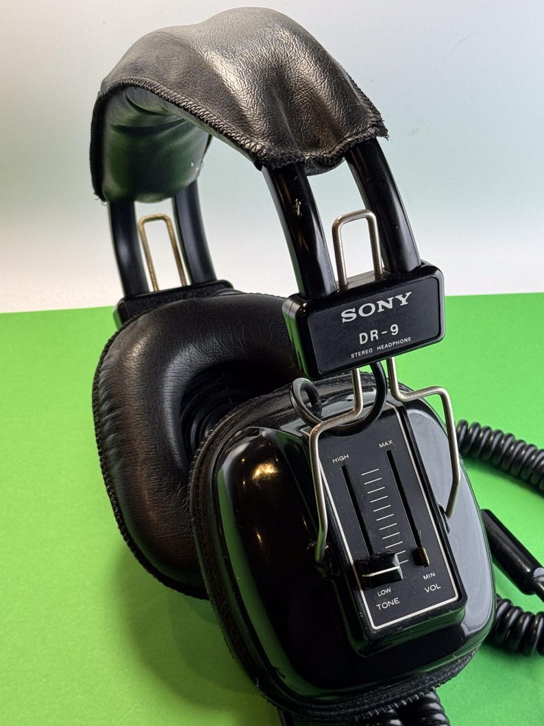 Pu&ograve; includere: Cuffie stereo Sony DR-9 nere con fascia in pelle nera e manopola di controllo del volume e del tono. Le cuffie hanno un cavo a spirale.
